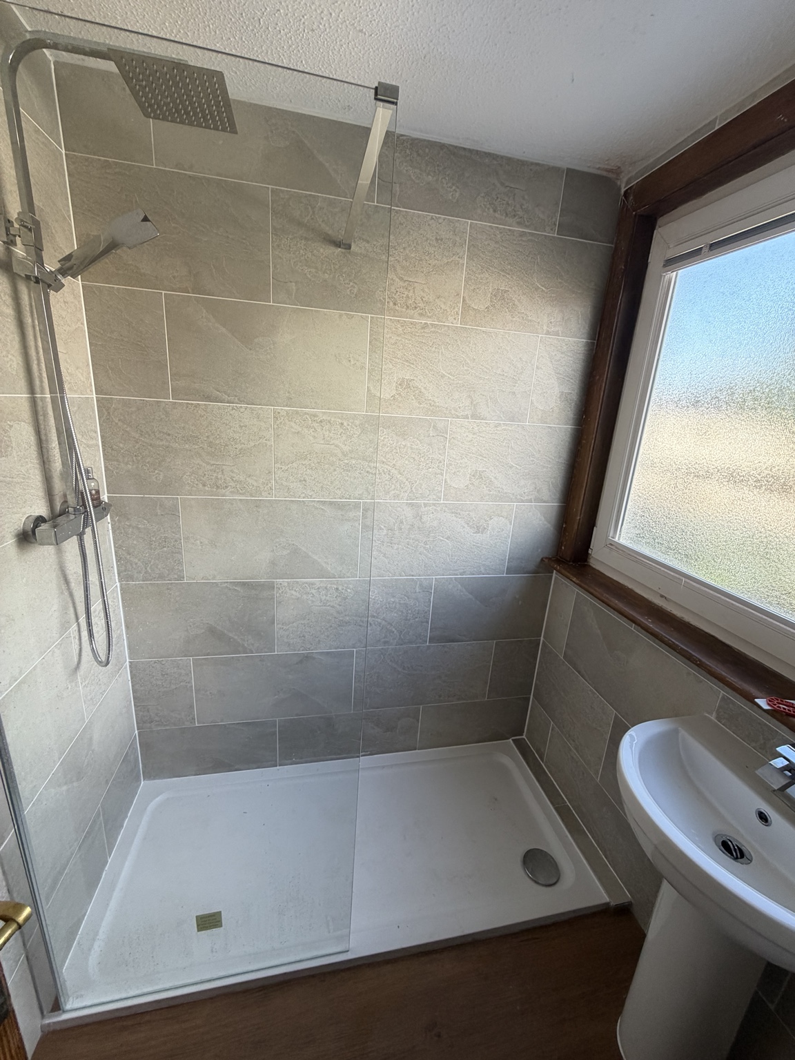 Walk-in shower with glass screen, rainfall shower head and grey wall tiles