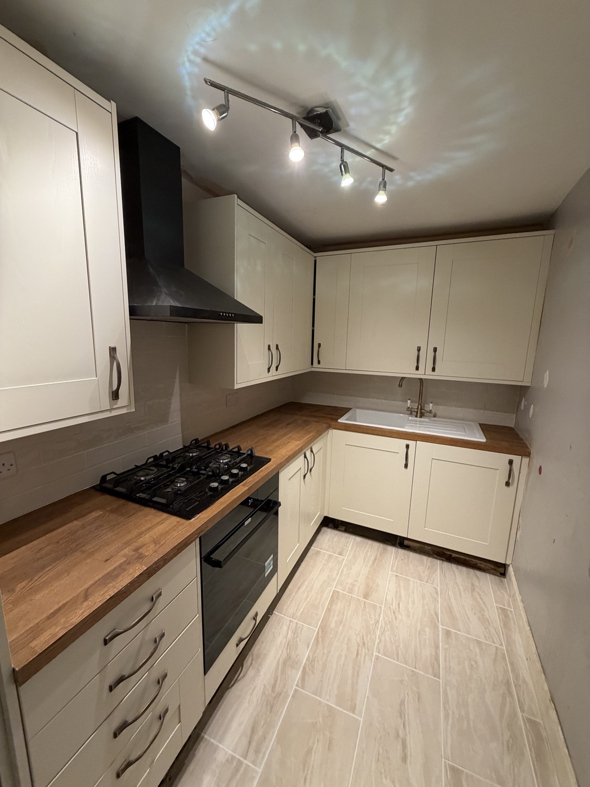 Cream shaker kitchen with timber worktops, black extractor and tiled floor