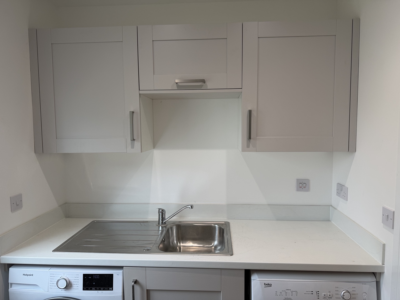Light shaker wall cabinets, pale worktop and stainless steel sink